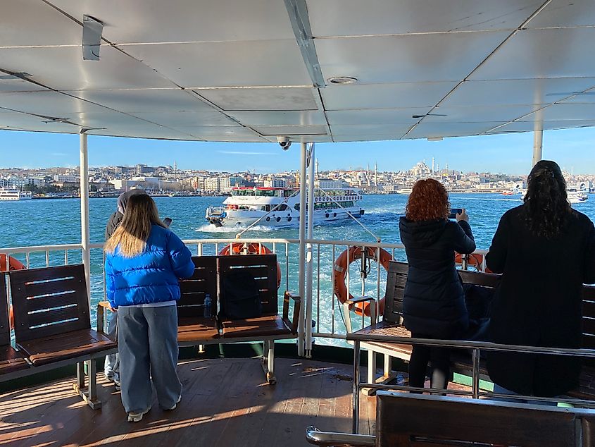 Ferry passengers take pictures of Istanbul's busy Bosphorus Strait from the back of the boat.