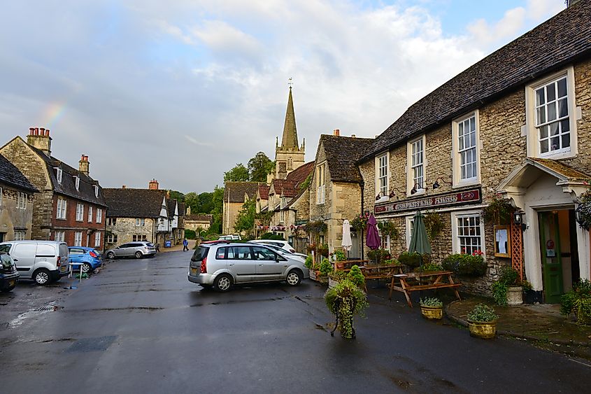 A traditional pub and houses are seen on a street in the village in Lacock, UK.