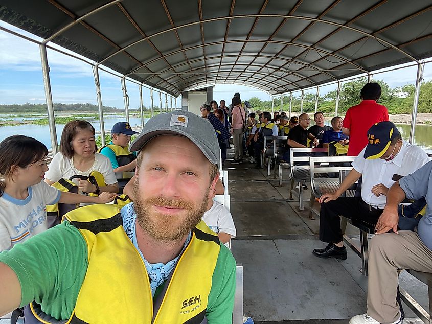 A man takes a selfie aboard a packed wetland tour boat.