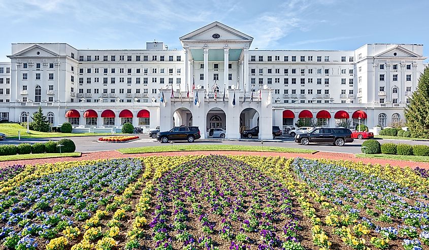 Greenbrier Hotel resort exterior entrance with landscaped flowers, lawn, cars, in West Virginia