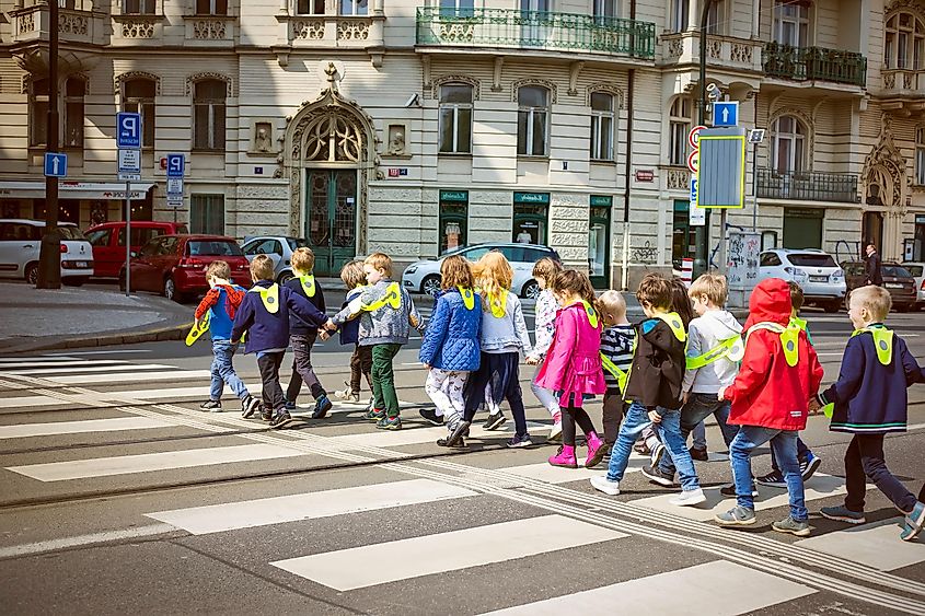 PRAGUE-CZECH REPUBLIC-APRIL-17-2018:Group Of School Children Crossing Road On Crosswalk With Traffic at Prague,Czech Republic