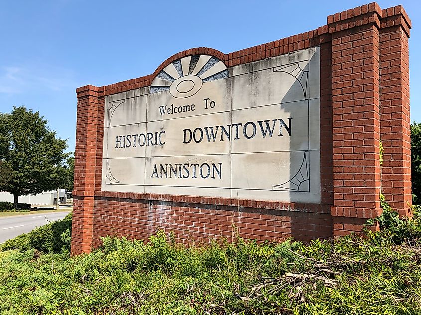 The photograph captures the welcoming sign for the city of Anniston, Alabama, standing proudly against a vibrant blue sky.