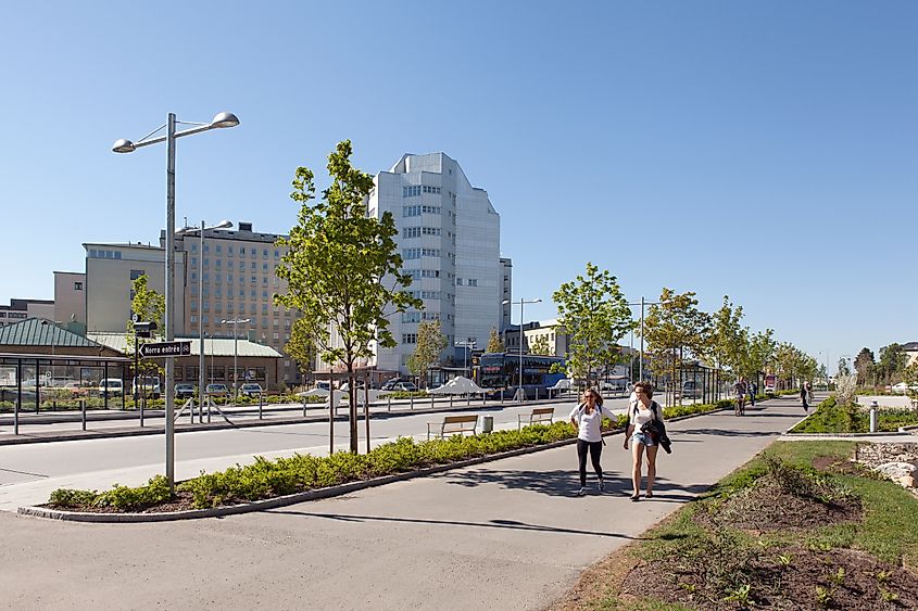 Entrance area of Norrland University Hospital (NUS) in Umeå, Sweden, with a bus station, park, and pedestrians on the walkway.