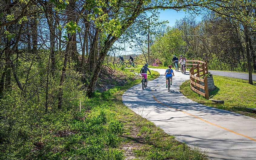 Семья с детьми катается на велосипеде по велосипедной дорожке в Белла Виста, Северо-западный Арканзас