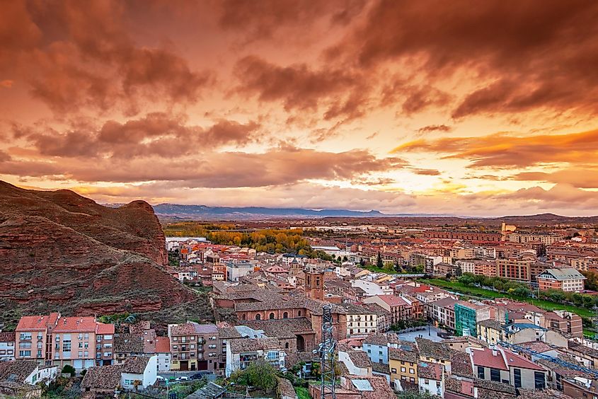 A red sky over a red-roofed Spanish town, next to the red cliffs of the La Rioja region