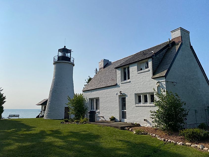 A lakeside lighthouse. Both the tower and corresponding keeper's dwelling are white washed.