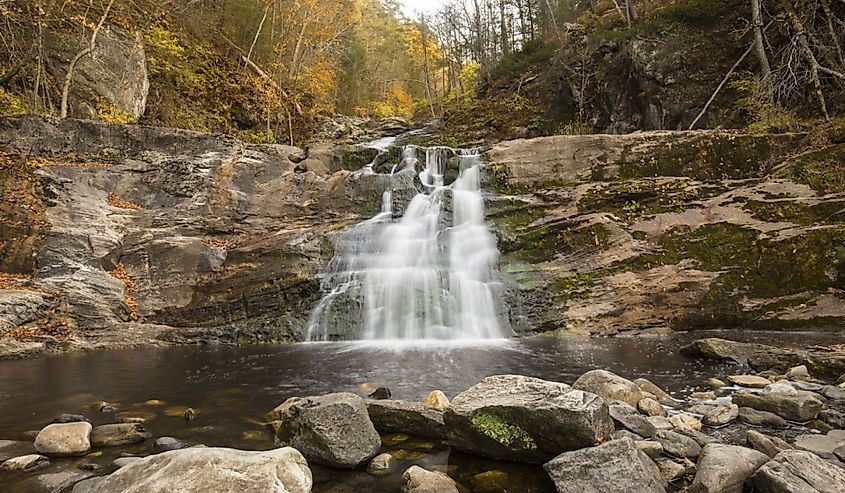 Blurred long exposure of the main waterfall at Kent Falls State Park in Kent, Connecticut, with fall foliage on the banks of Falls Brook.