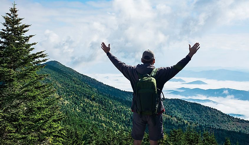 Man with arms raised relaxing on spring hiking trip.