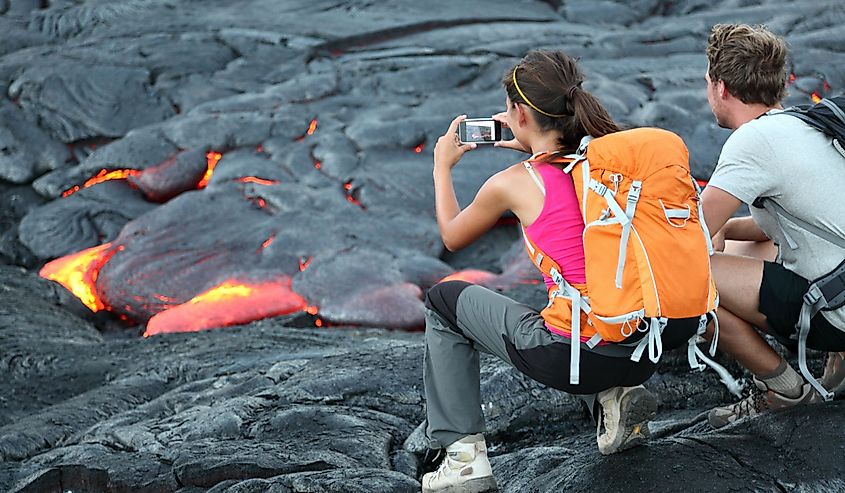 Tourists taking photo of flowing lava from Kilauea volcano around Hawaii Volcanoes National Park, USA
