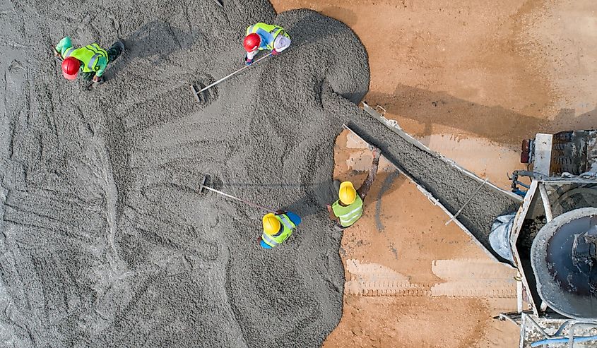 A construction worker pouring a wet concrete at road construction site