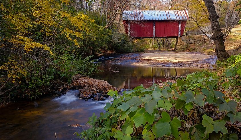 Campbell's covered bridge in Greer, South Carolina, USA with fall foliage and smooth water in stream