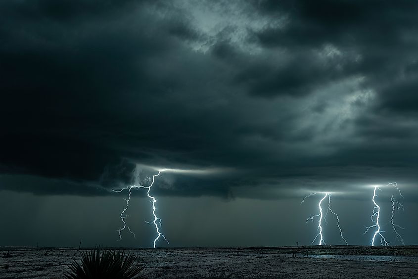 A mesocyclone lightning storm with dark clouds forming over the plains in Tornado Alley, Oklahoma at night. Via Shutterstock / Joe Belanger