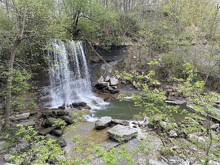 A wide waterfall drops into a lush, open gorge 