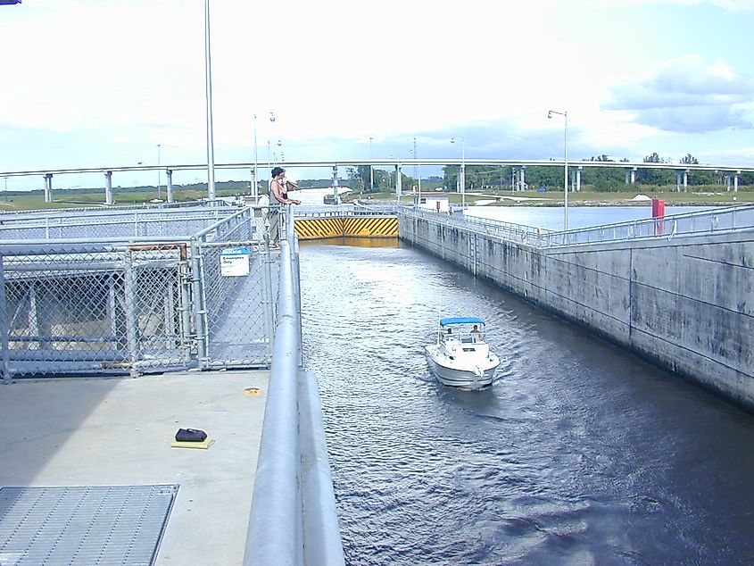 Boater exits as canal-side gates closed behind and Lake Okeechobee lakeside gates opening.