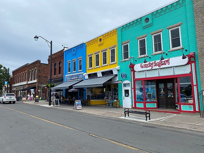 Alternating, colorful, monochrome brick buildings line a small town commercial street.
