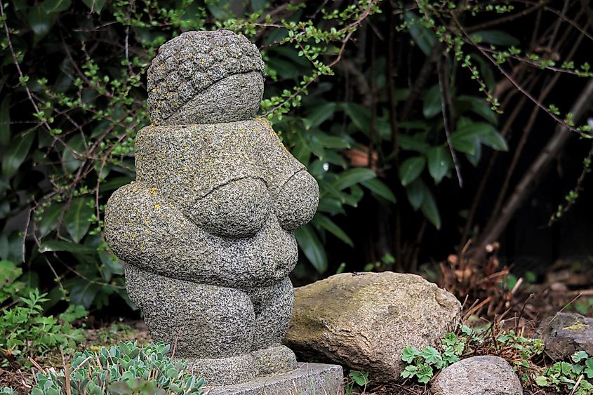 A statue of ”Venus from Willendorf” in a swedish garden in the spring blooming.