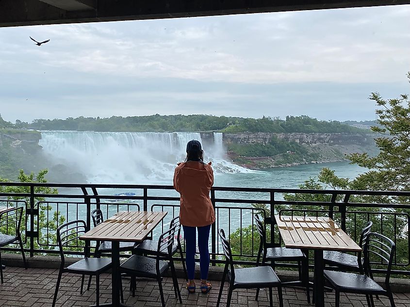 A woman with wet hair looks out over the American and Bridal Veil Falls after a boat cruise.