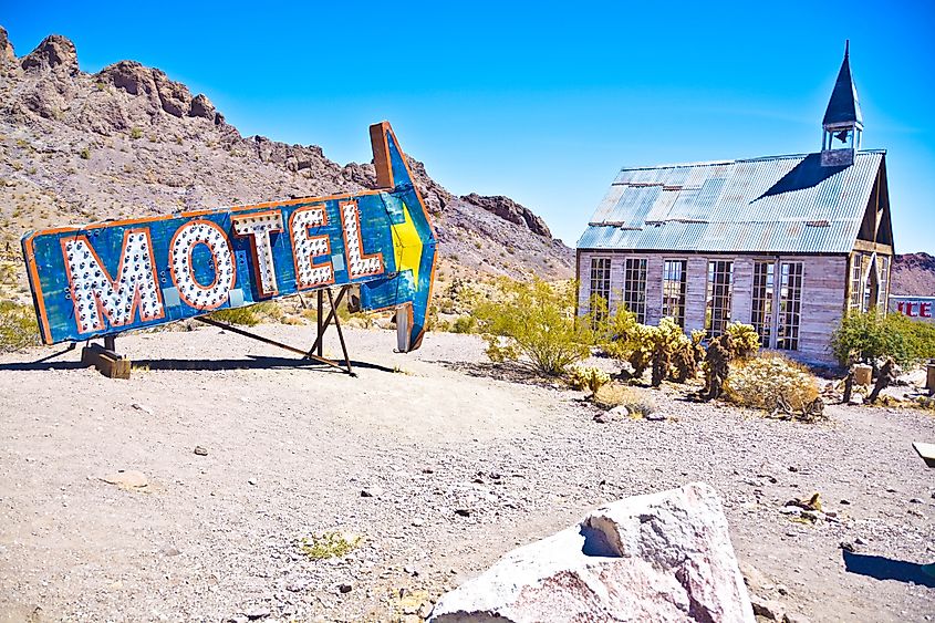 Editorial Photo Credit: Nature Freeze Framed via Shutterstock. Old motel sign pointing towards old church in Nelson Ghost Town Nevada