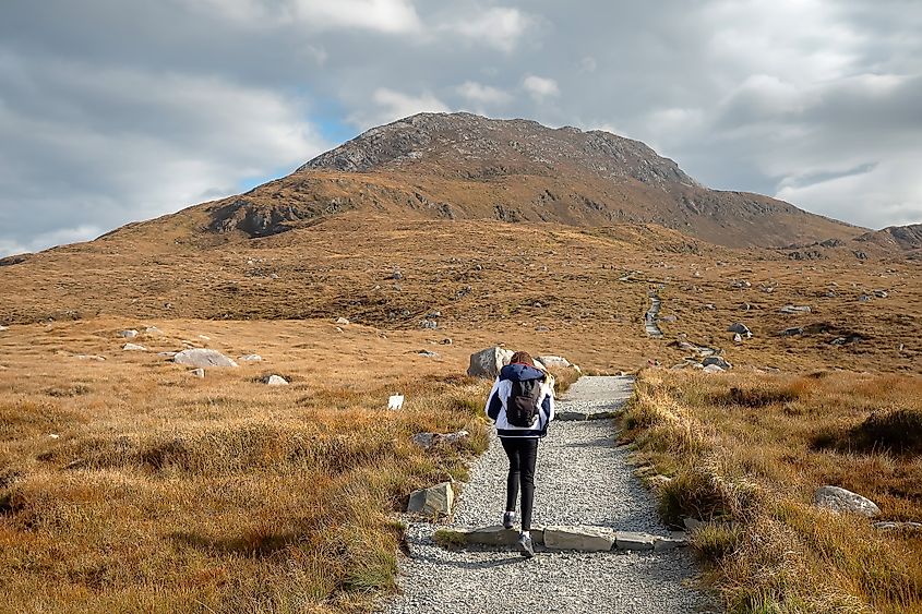 Young teenager girl walking on a path to climb Diamond hill in Connemara National Park.