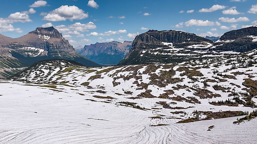 Snowy Logan Pass trail in Glacier National Park on a sunny day