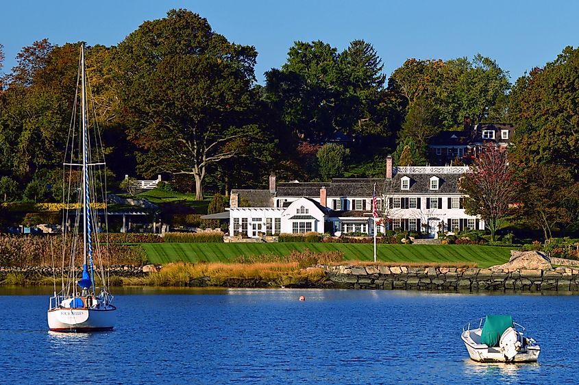 A sailboat and small outboard motor boat is moored off of a waterfront estate in Greenwich Connecticut , via James Kirkikis / Shutterstock.com