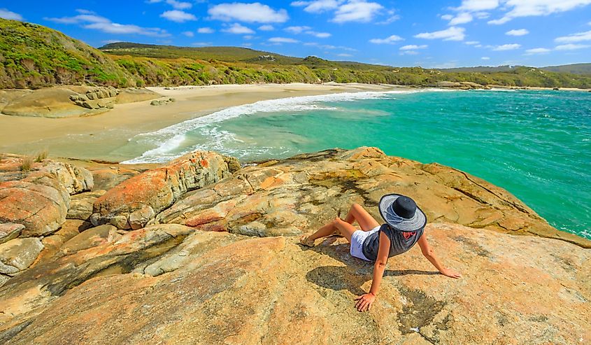 Woman in hat sunbathing on the rocks of Waterfall beach in Denmark, Western Australia.
