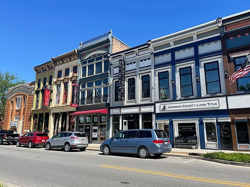 Historic downtown street with colorful, ornate building facades, displaying signs for a boutique and land title office. Cars line the sunny street.