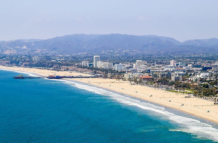 Aerial view of Santa Monica State Beach, with residential buildings, Santa Monica Pier and mountains