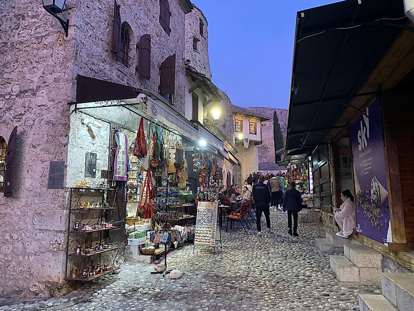 An early evening stroll through the cobbled street of Mostar's bazaar. Vendors and cafes line both sides.