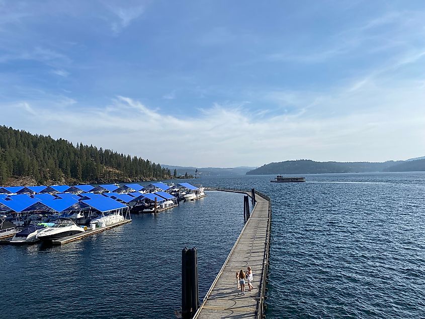 A large wooden boardwalk wraps around a large lake marina. 
