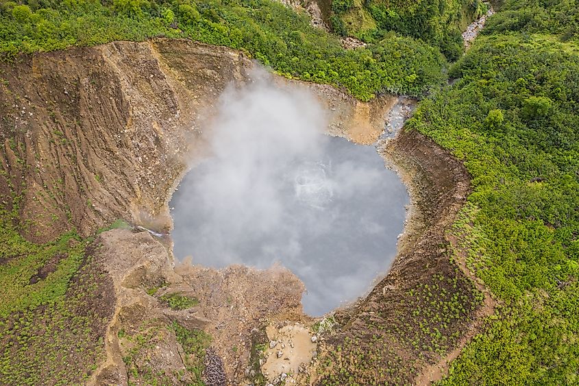 Aerial view of Boiling Lake in Morne Trois Pitons National Park, Dominica, showing the steaming volcanic lake surrounded by rocky crater walls and dense green rainforest.