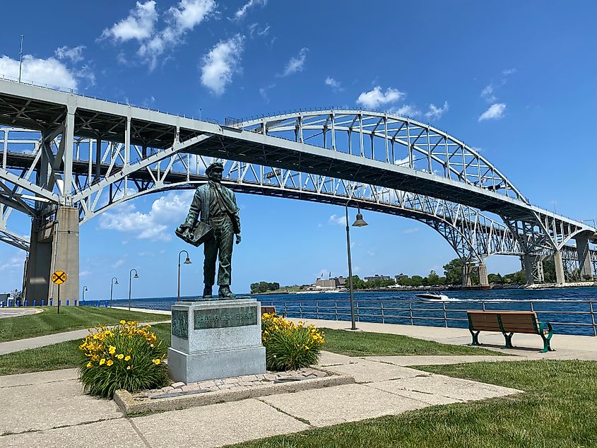 A statue of Thomas Edison stands beneath twin steel bridges