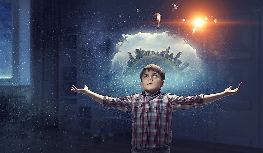 There is so much to learn. Young boy with hands in the air, universe surrounding him.