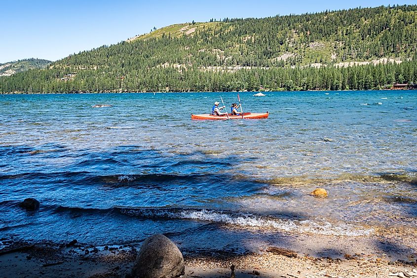 Two kayakers paddling an orange boat in Donner Lake , California during the summer months