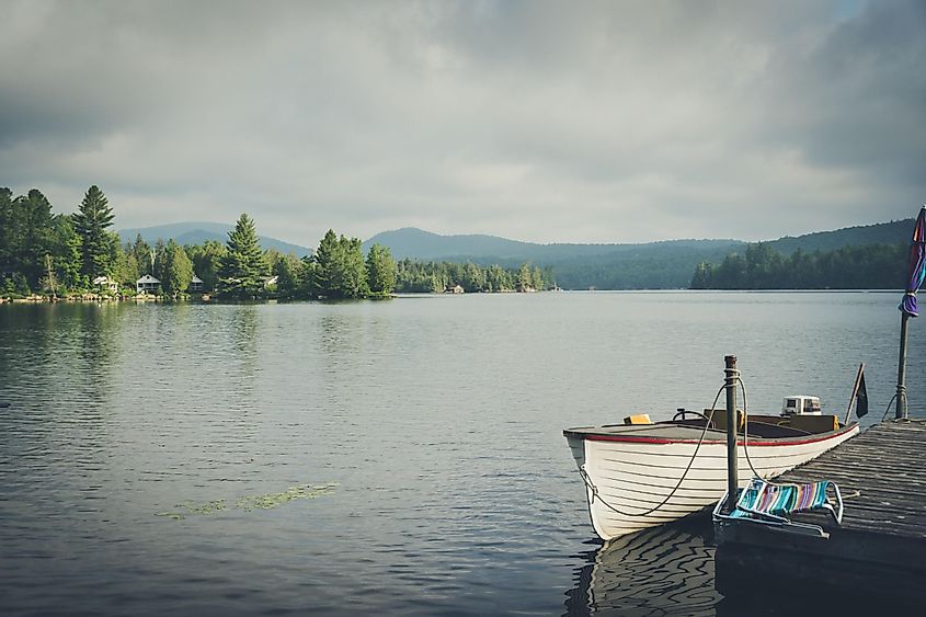 A boat sits on Blue Mountain Lake in a moody summer scene in Indian Lake, New York