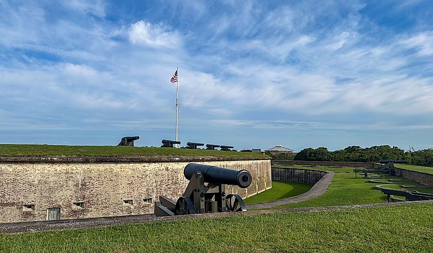 Row of historic cannons positioned along the grassy ramparts of Fort Macon State Park in North Carolina