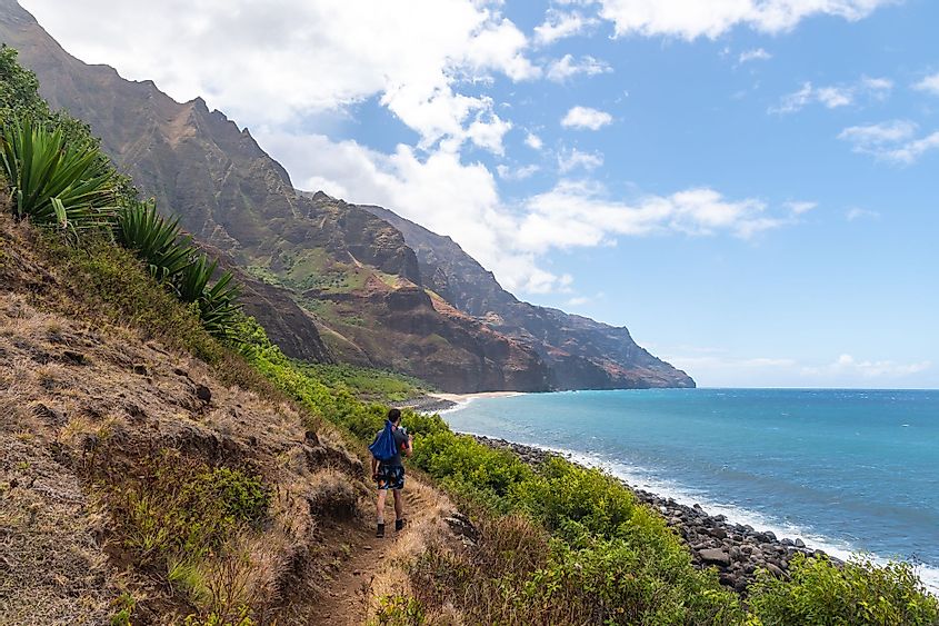 A young man hiking along the Kalalau Trail in the Na Pali Coast State Park in Kauai, Hawaii