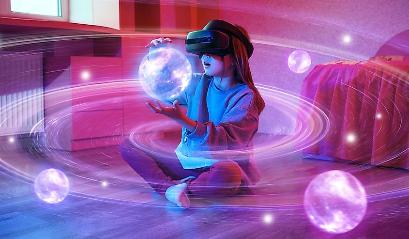 Child girl wearing virtual reality headset and looking at digital space system with planets or Universes.