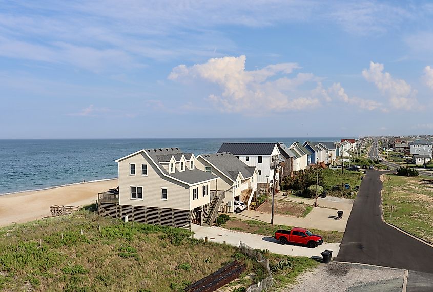 A wide aerial view of homes that stand along the Atlantic Ocean sand dunes and Highway 12 in the Outer Banks, via Ant DM / Shutterstock.com