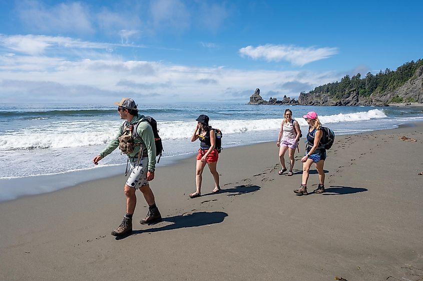 Hikers on Shi Shi Beach Trail in Olympic National Park near Neah Bay, Washington on sunny summer afternoon with Point of Arches in background.