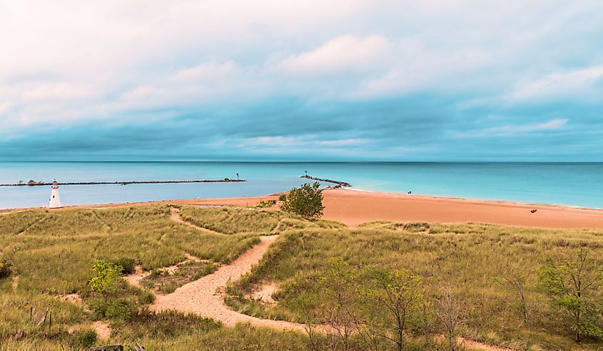 Sandy dunes and grass in the harbor at New Buffalo, Michigan on the lake. Dramatic sky front coming in before it rains on a hilly sandy path leading to the beach.