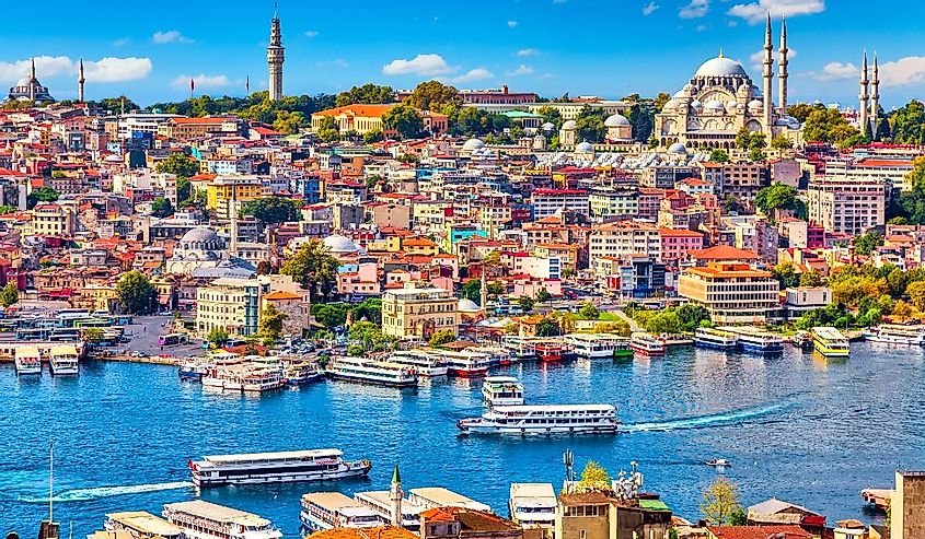 Touristic sightseeing ships in Golden Horn bay of Istanbul and mosque with Sultanahmet district against blue sky and clouds
