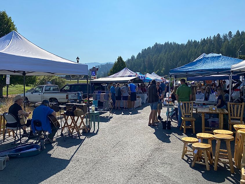 Two musicians play to the vendors and patrons of a parking lot farmers market.