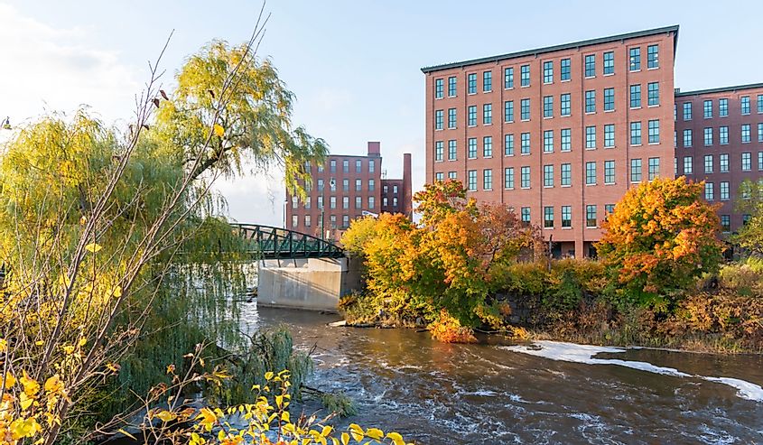 Autumn foliage of scene of Presumpscot river in front of an old brick building with Blacks bridge in Westbrook, Maine.