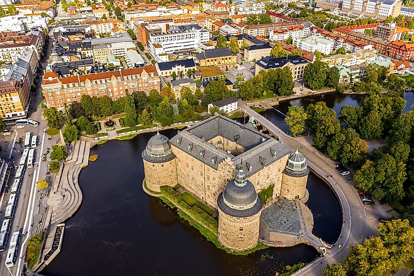 Aerial view of Örebro Castle surrounded by the Svartån River, with the cityscape of Örebro, Sweden, in the background.