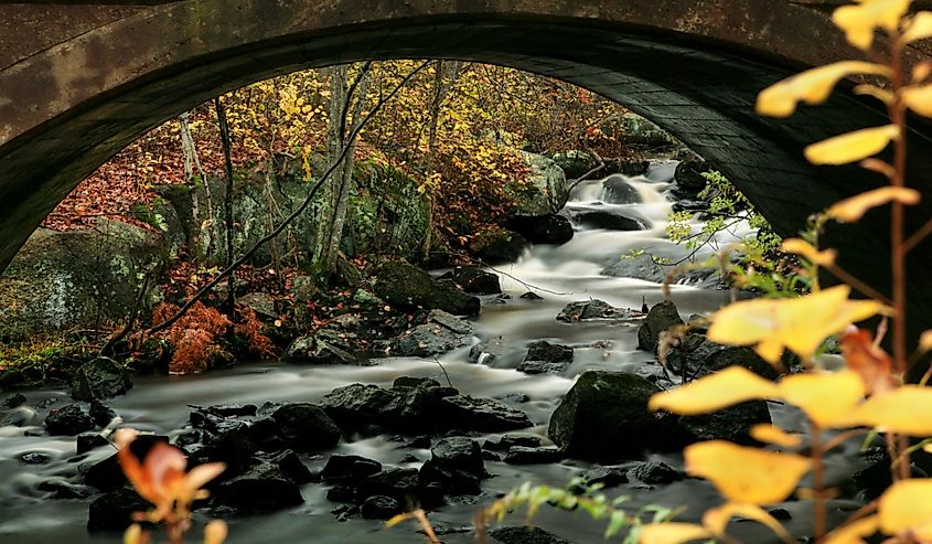 Long exposure photography of a babbling stream flowing under a bridge in Arcadia State Park, Hope Valley, Rhode Island