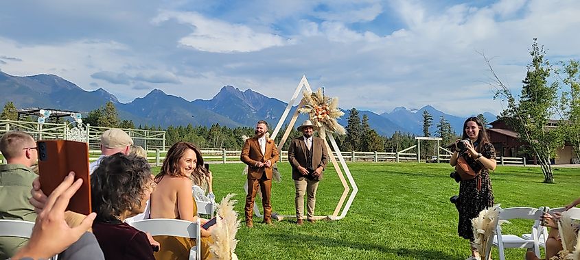 Outdoor wedding ceremony with guests seated on a lawn beneath mountain views in Ronan, Montana.