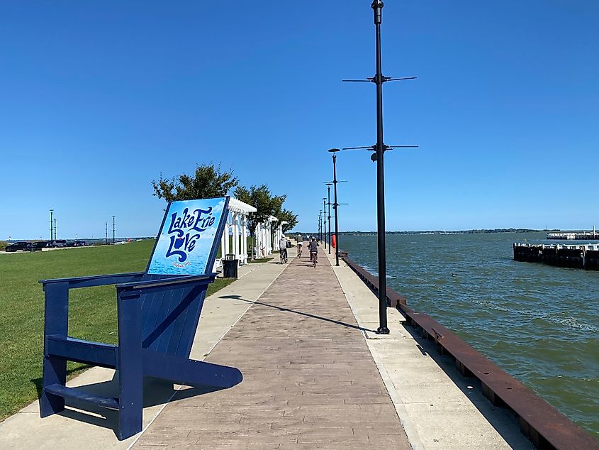 A family bikes along a pier, past a large blue cottage chair branded "Lake Erie Love."