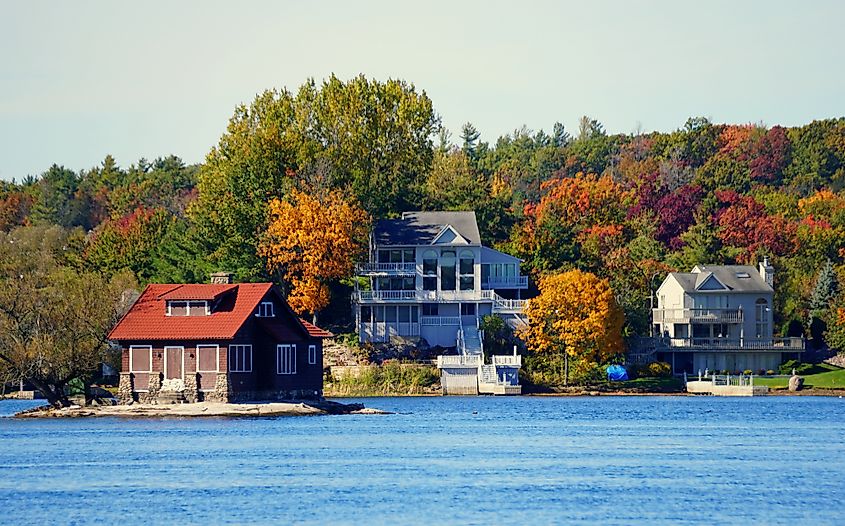 Waterfront homes surrounded by striking fall foliage along the St. Lawrence River.