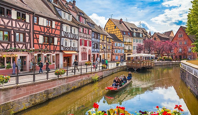 Beautiful view of the historic town of Colmar, also known as Little Venice, with tourists taking a boat ride along traditional colorful houses on idyllic river Lauch in summer, Colmar, Alsace, France